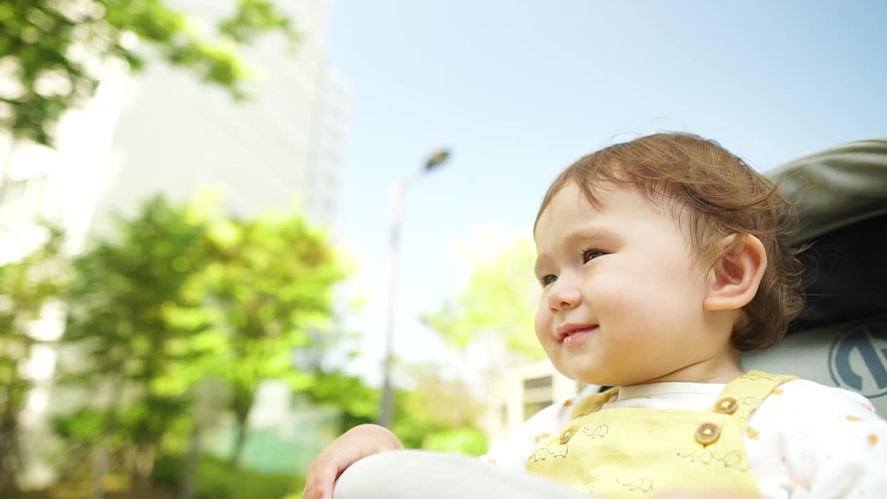 유모차나 유모차, 아기 교육 개념에 앉아 있는 동안 한국에서 인사하는 문화적 몸짓으로 고개를 숙이는 행복한 혼혈 외국인 아기 소녀의 슬로우 모션