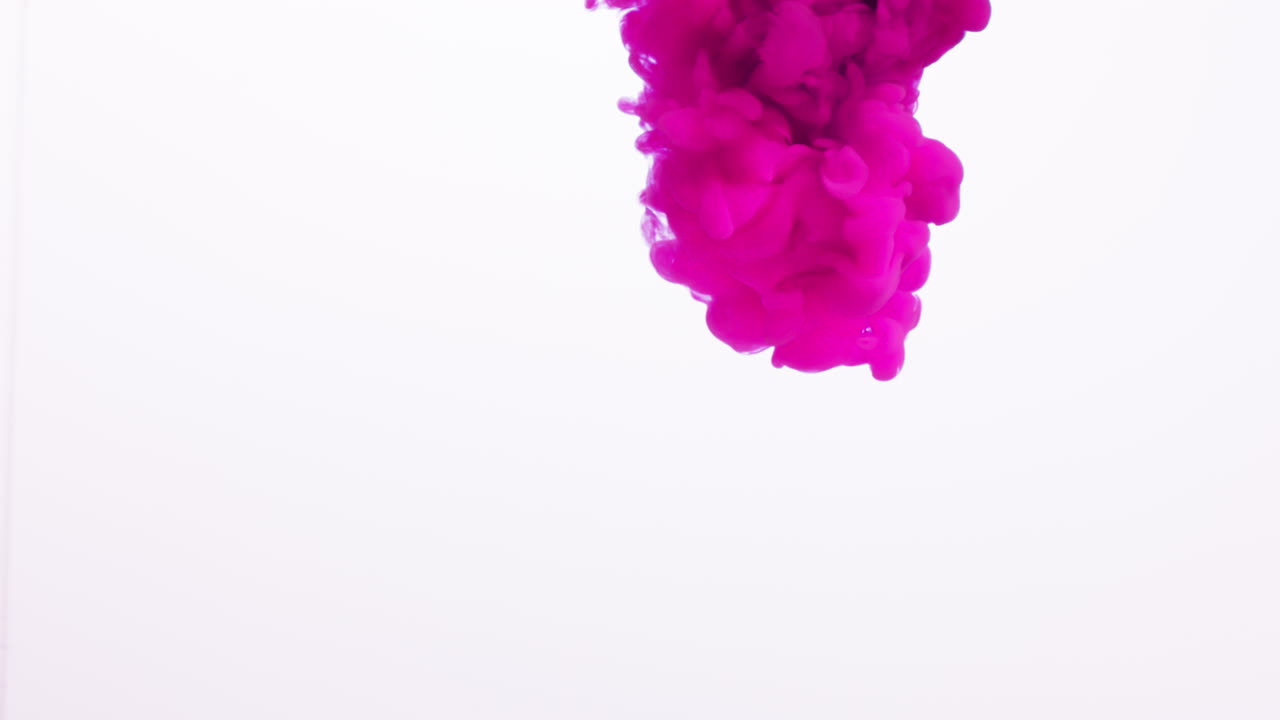 pintura o tinte rosado caído en agua contra un fondo blanco para crear un fondo de humo de colores giratorios 2