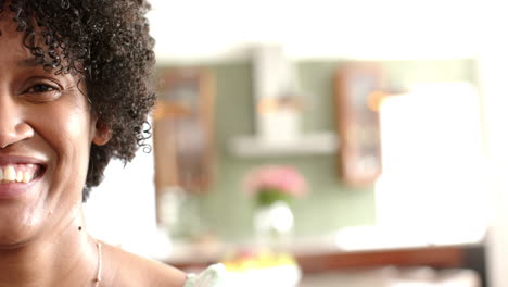 Half-portrait-of-happy-african-american-woman-smiling-in-sunny-living-room,-copy-space,-slow-motion