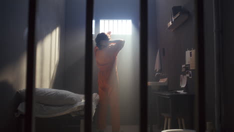 man walking around prison cell, looking through window and resting on bed