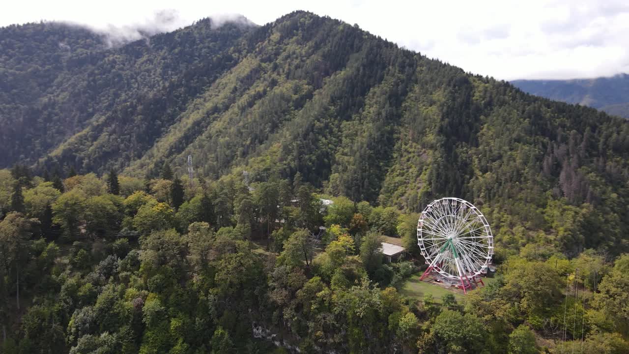 vista aérea de la rueda gigante en la cima de las montañas rodeada de bosque nube niebla valle ciudad