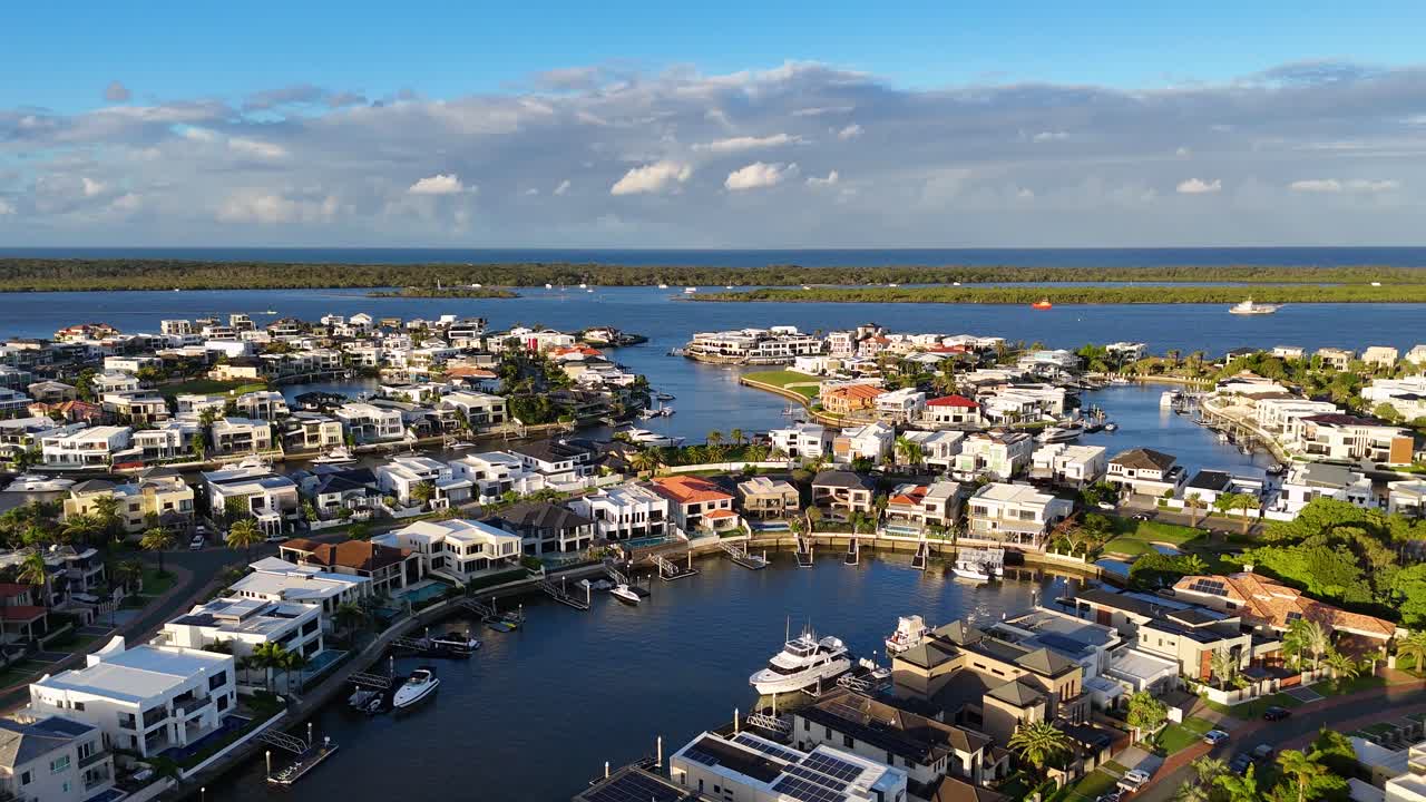 Drone footage captures luxury estates and waterways at Gold Coast, Australia, under bright daylight with clear skies