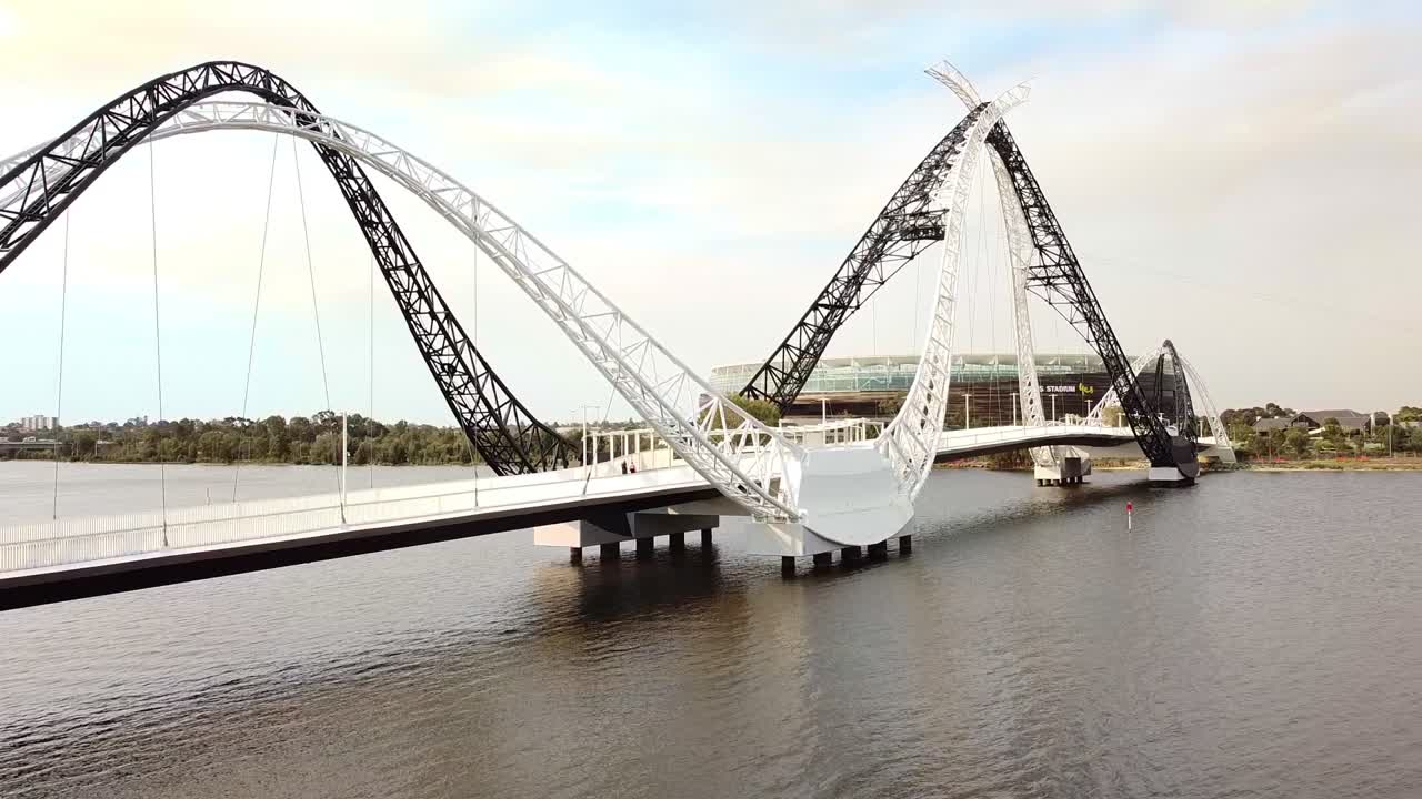 Aerial ascending view of the Matagarup pedestrian bridge over the Swan River with Perth Stadium in the background