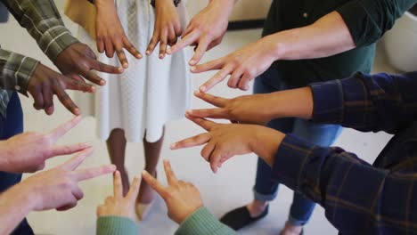 Diverse-business-people-teaming-up-with-hands-together-at-office