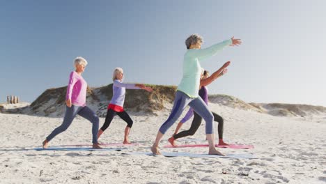 athletic women performing yoga in the beach