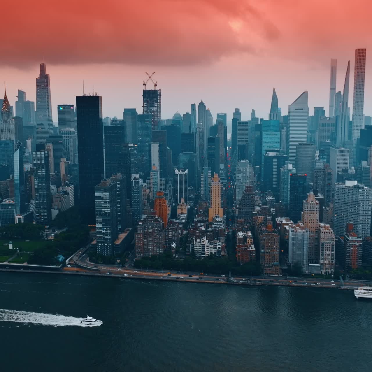 Cielo rosa e paesaggio di nuvole pesanti sopra il centro di New York. Filmato aereo sopra il fiume con yacht galleggiante