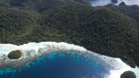 view on lagoons, island with white sand beach, rock formations and phinisi ship in raja ampat, wayag, indonesia