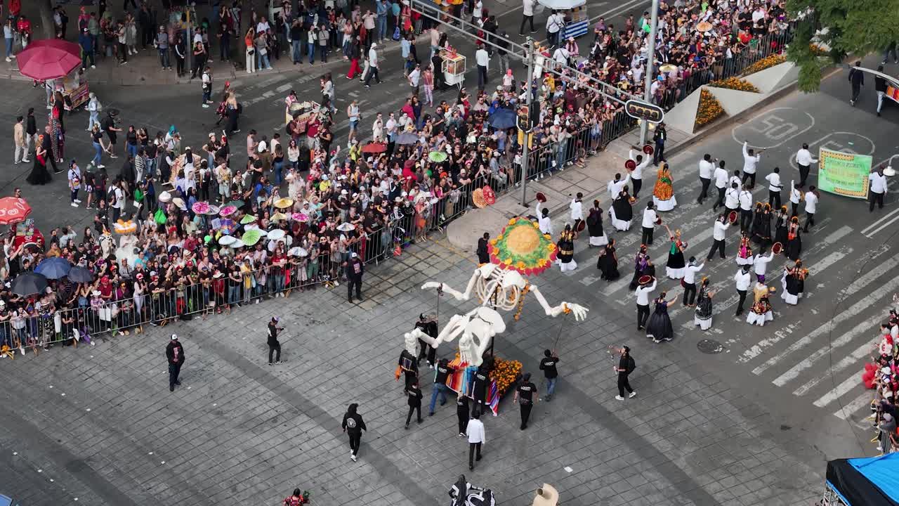 Aerial shot of a skull-shaped Mojiganga concluding its participation in the Day of the Dead parade at the Angel of Independence roundabout in Mexico City