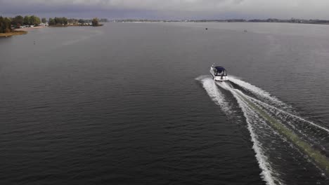 Speedboat-crossing-the-drone-shot-while-proceeding-on-full-speed-on-a-fairway-at-wide-streched-lake-on-a-cloudy-day-in-the-netherlands