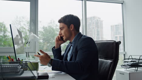 Nervous-manager-talking-phone-at-glass-workplace.-Angry-man-throwing-papers