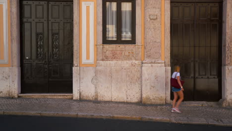 a girl is walking through the frame in front of an iconic wall in lisbon, portugal