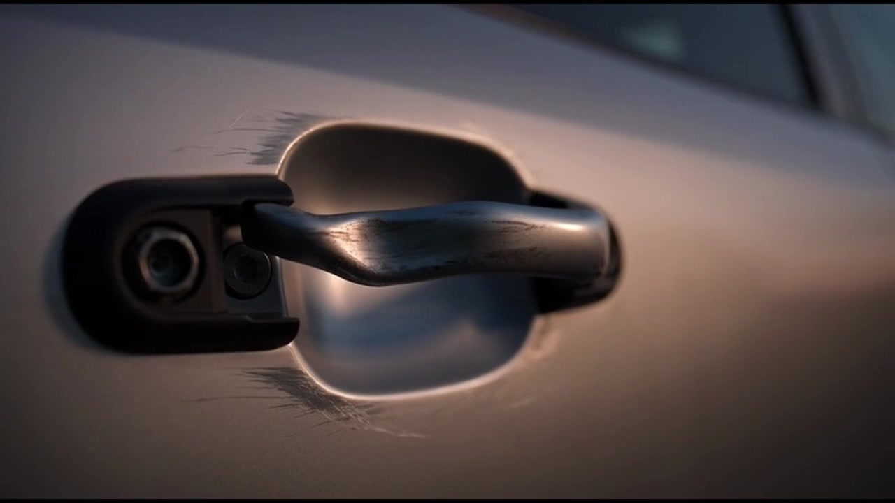 Primo piano della maniglia della portiera dell'auto graffiata al tramonto