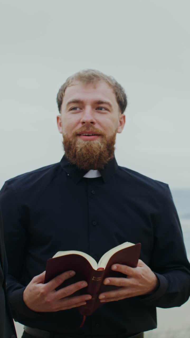 Wedding ceremony on the beach with priest and couple kissing