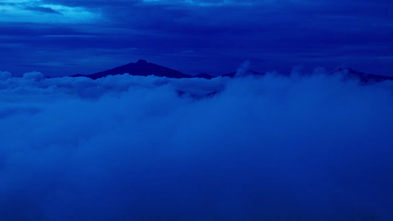 DRONE: DOLLY IN SHOT OF CLOUDS AND THE MOUNTAINS OF URUAPAN AT DUSK