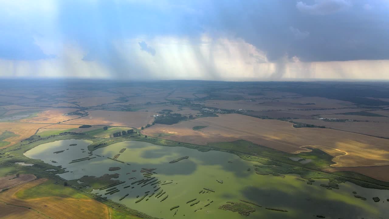 vuelo aéreo hacia atrás sobre los campos agrícolas y los humedales durante la tormenta