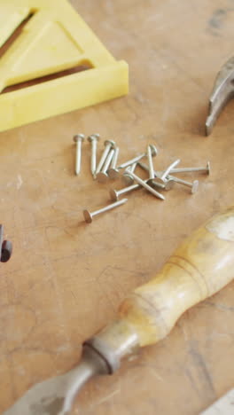 various tools and nails are scattered on a wooden surface