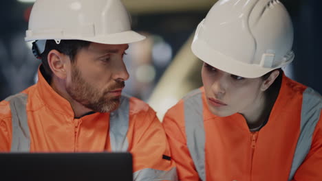 ingenieros centrados en la búsqueda de portátiles comprobando el proyecto de producción en la fábrica de cerca