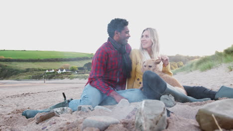 loving couple with dog relaxing by fire on winter beach vacation