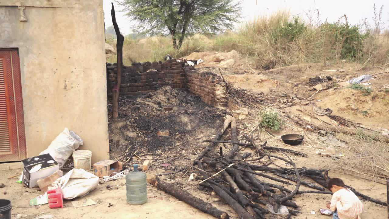 Within the village, lies a humble home that contains various possessions, goats, and a burnt house.