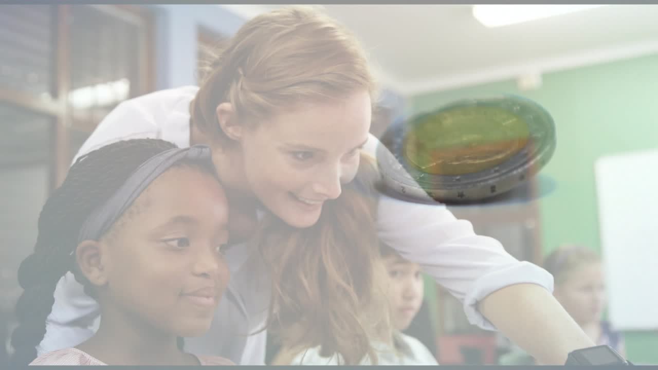 Student typing on keyboard in school lab when teacher leaning over shoulder and pointing at monitor