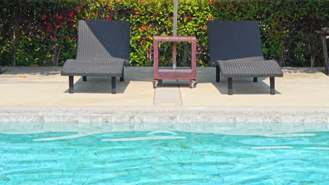 empty sun loungers on the edge of a swimming pool