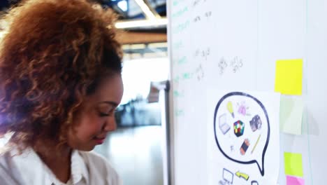 Woman writing on whiteboard and using digital tablet