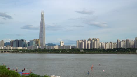 people enjoying windsurfing and paddleboarding at han river with seoul skyline in the background in south korea