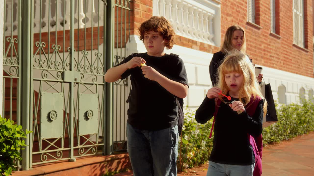 Children playing with bubbles on a sidewalk with an adult
