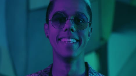 close-up view of stylish young african american man in sunglasses smiling at the camera outdoors at night