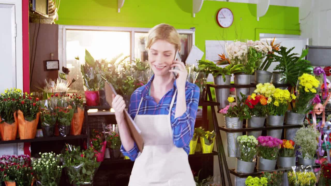 Fiorista femminile che prende ordine sul telefono cellulare nel negozio di fiore