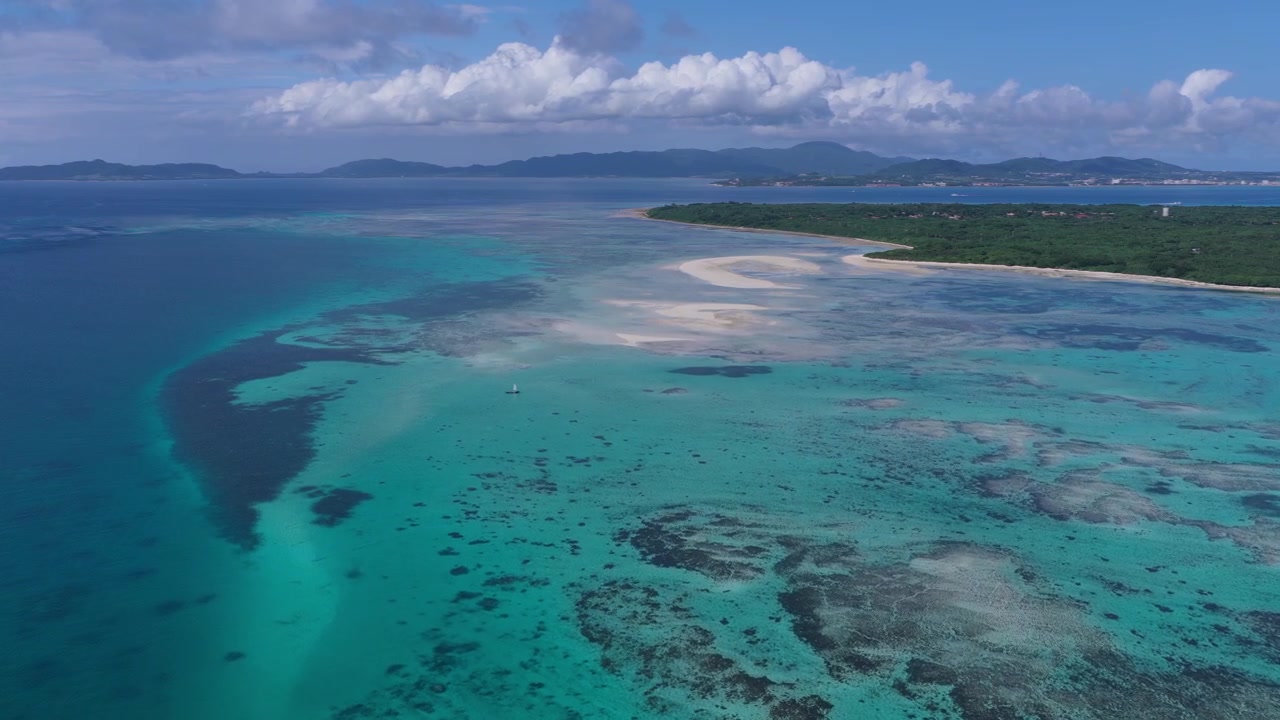 Ripresa orizzontale in primo piano con carrello in avanti, rivolta a destra, sopra le acque turchesi, il banco di sabbia e la barriera corallina poco profonda vicino alla spiaggia di Kondoi, isola di Taketomi, Okinawa, Giappone