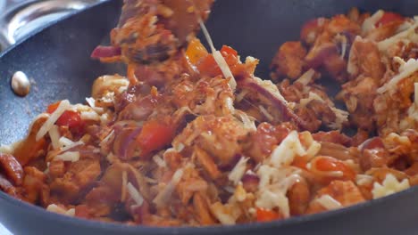 Close-up-on-hot-steaming-pan-on-cooker-stove-filled-with-red-sauce-covered-nutritious-vegetables,-chicken---melting-grated-cheese-mixture