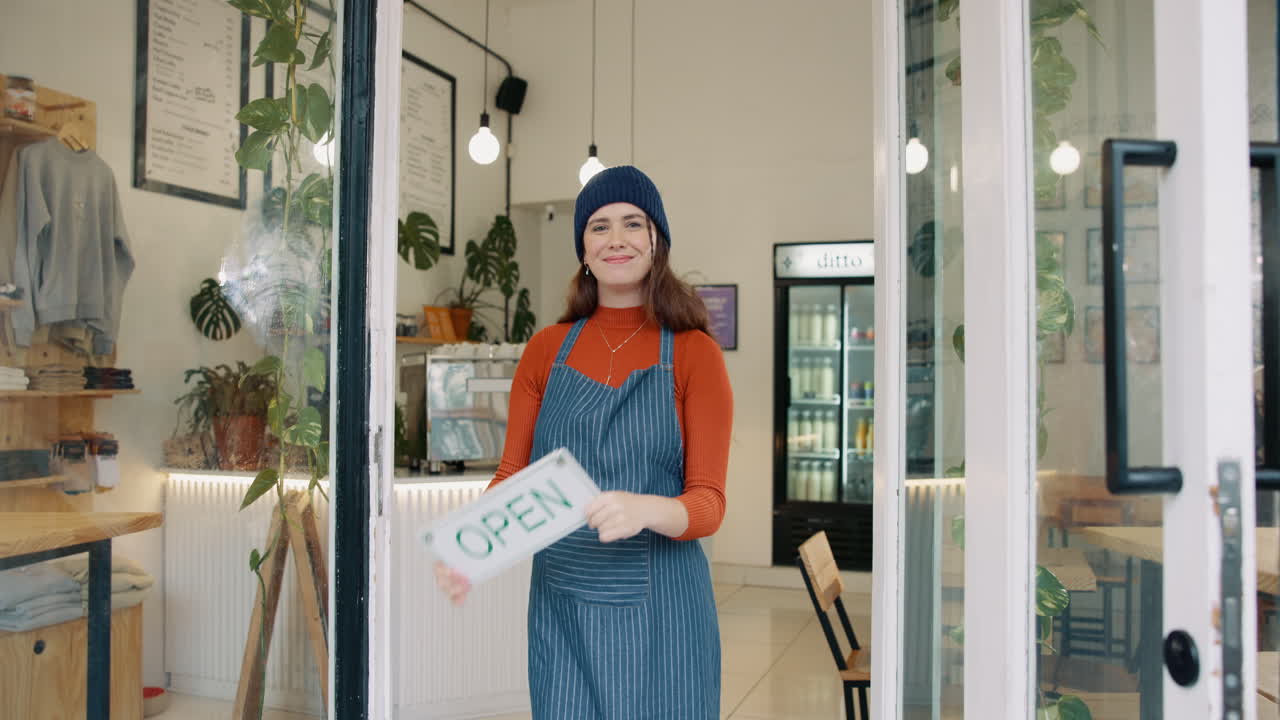 Donna che tiene un cartello 'aperto' nella sua caffetteria