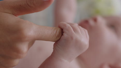 close up mother holding baby hand touching fingers nurturing newborn caring for infant enjoying motherhood connection with child