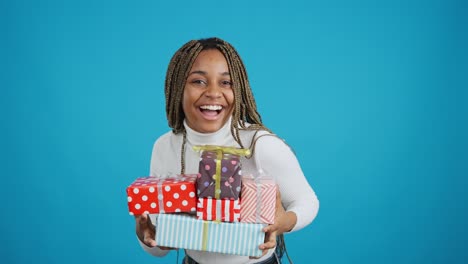 a happy young woman holding a stack of colorful gifts