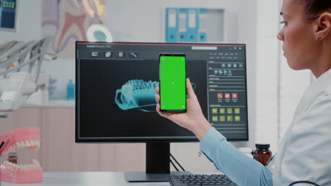 mujer trabajando como dentista con pantalla verde en el teléfono inteligente