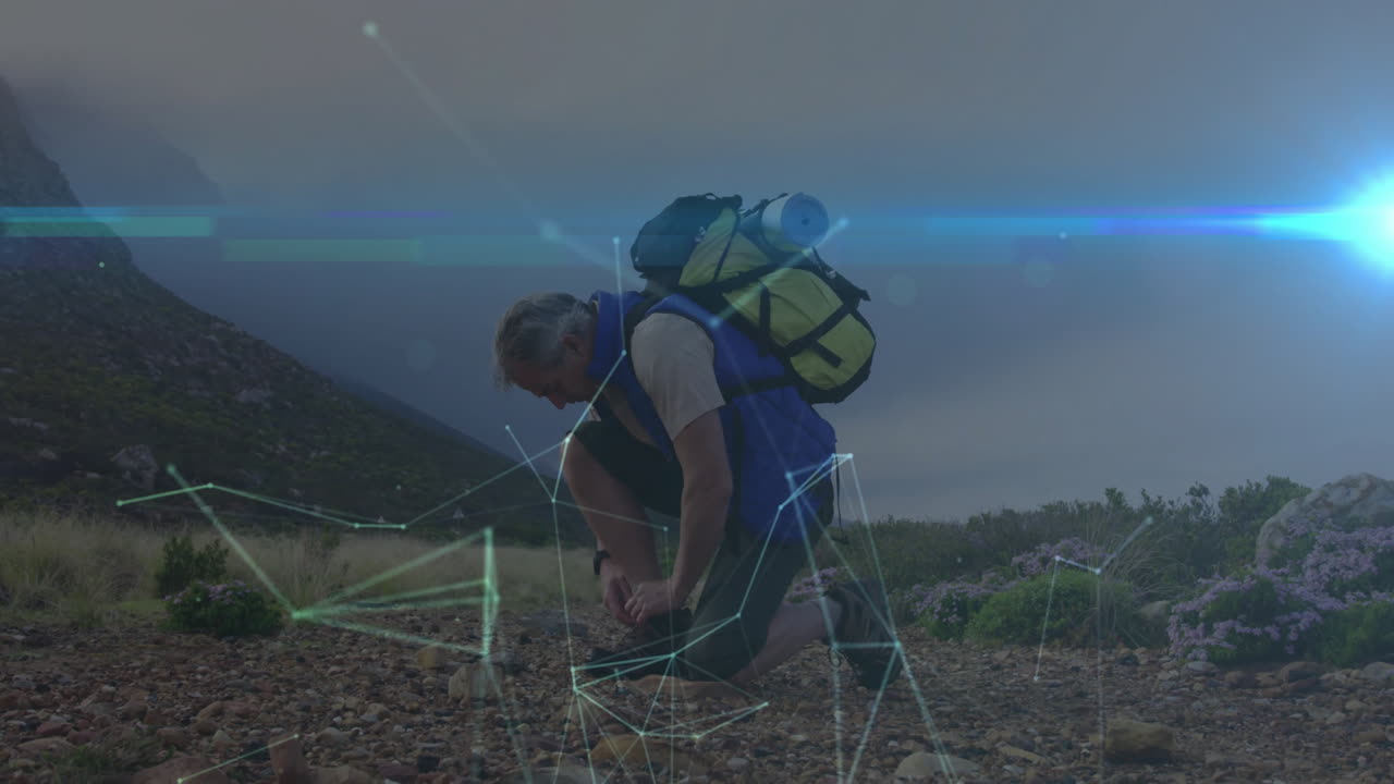 Mature hiker kneeling adjusting boot on rocky hillside, showcasing technology data overlay concept