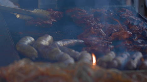 shallow focus tight shot of meats on a very smoky bbq grill