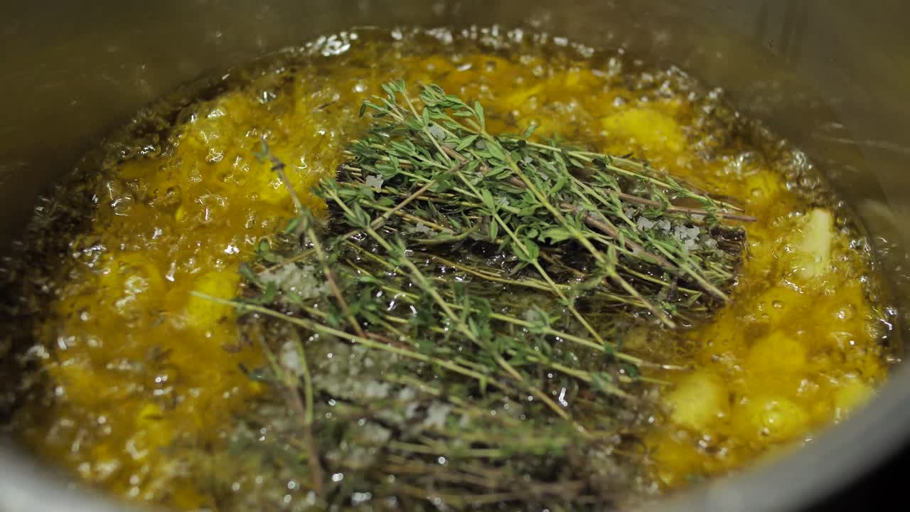 Frying chopped potatoes with fresh thyme in pot, close up