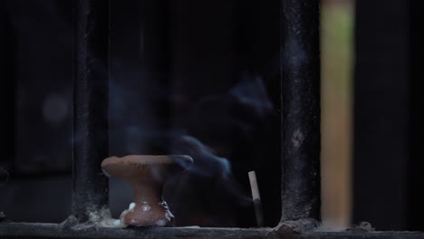 a stick of incense burning and giving off an aromatic smoke at a hindu temple in the city of kathmandu, nepal