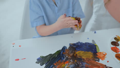 close-up children draw their fingers on paper using paints