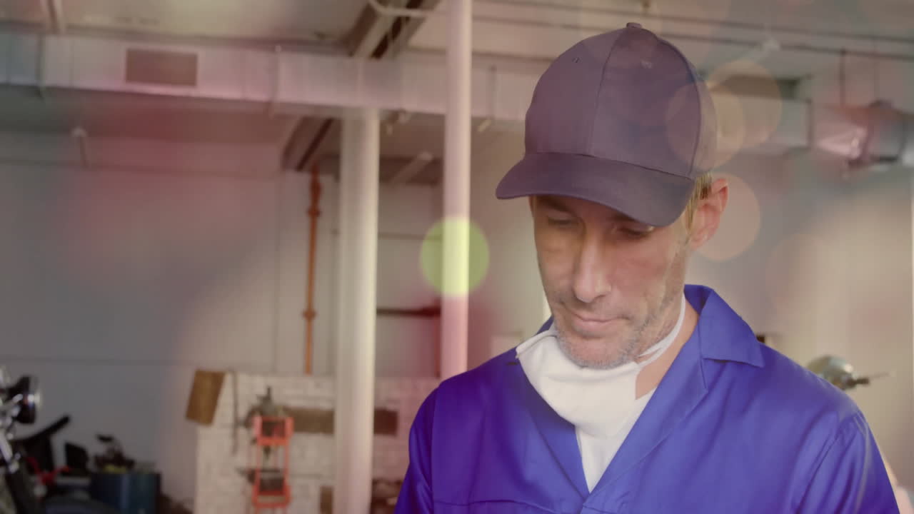 Mechanic in blue coveralls, black cap inspecting drill press in factory, with animated data charts