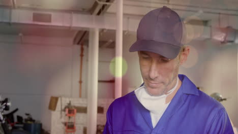 mechanic in blue coveralls, black cap inspecting drill press in factory, with animated data charts