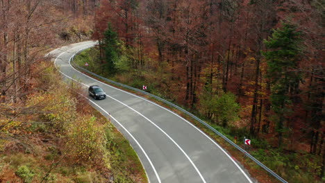 Aerial-birds-eye-footage-of-a-car-driving-through-a-forest-road