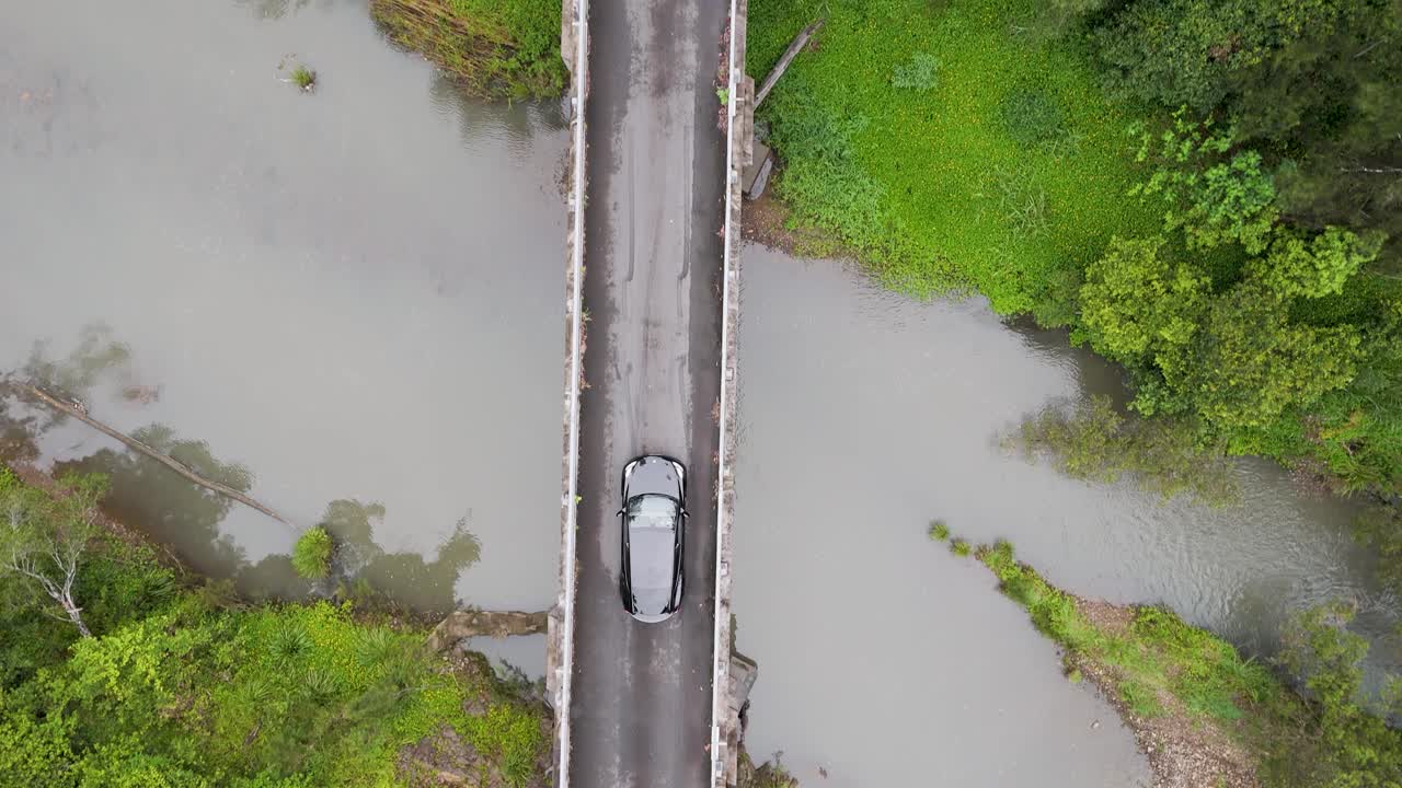 한 자동차가 숲의 다리를 지나간다.