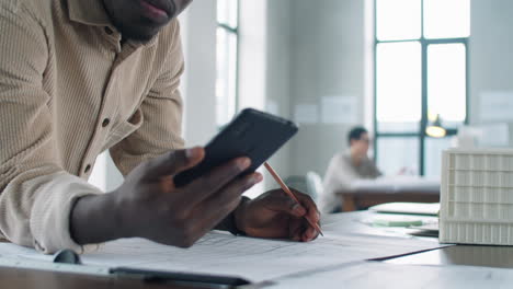 african american male architect drawing floor plan and using smartphone