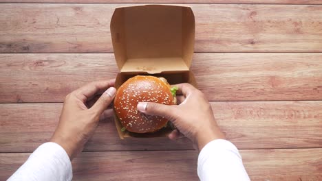 person eating a burger from a paper box