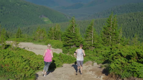 Extreme-Running-A-Woman-With-A-Personal-Trainer-Runs-Down-A-Steep-Mountain-Path-In-The-Mountains-Bac