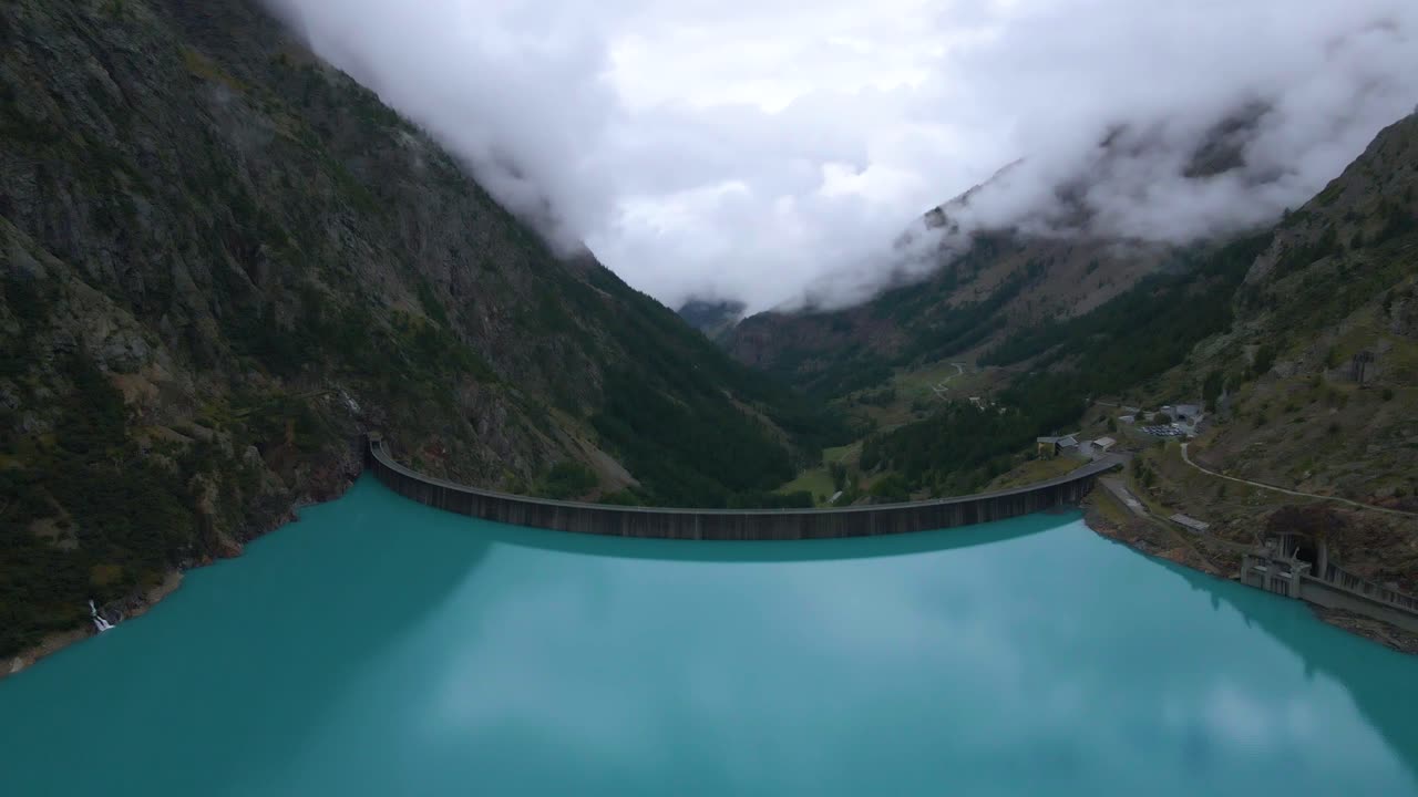 Drone shot flying over the Place de Moulin reservoir and dam in the Aosta province in Italy