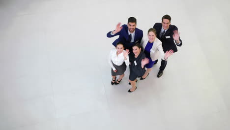 smiling businesspeople waving hands in office